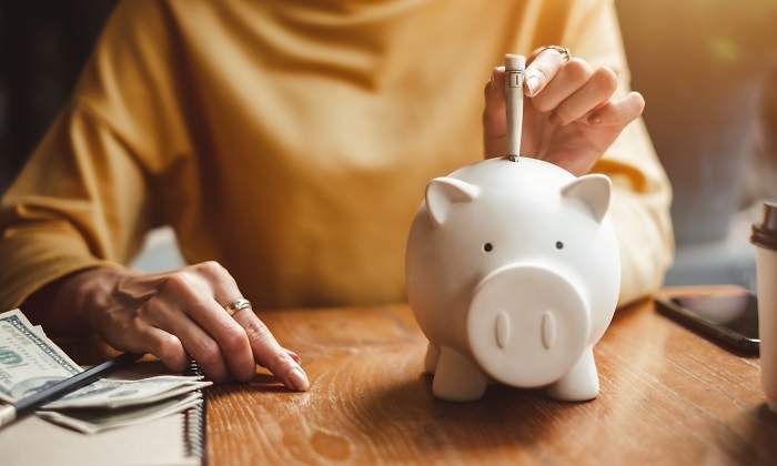 Una persona mete dinero en la hucha