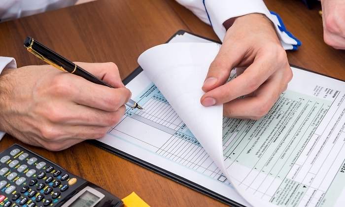 Una persona hace la declaracin de la renta ayudado por una calculadora