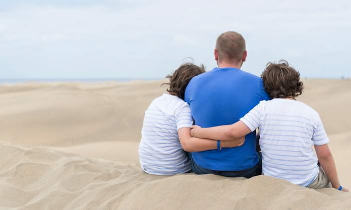 padre-espaldas-hijos-abrazan-playa-dreamstime.jpg
