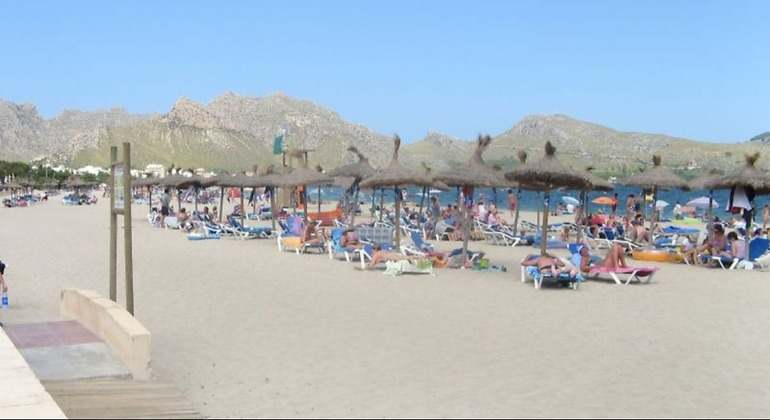 Foto de aguas cristalinas y sombrillas arena fina