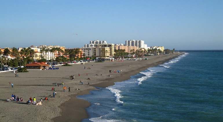 La playa repleta de bañistas en unas arenas oscuras