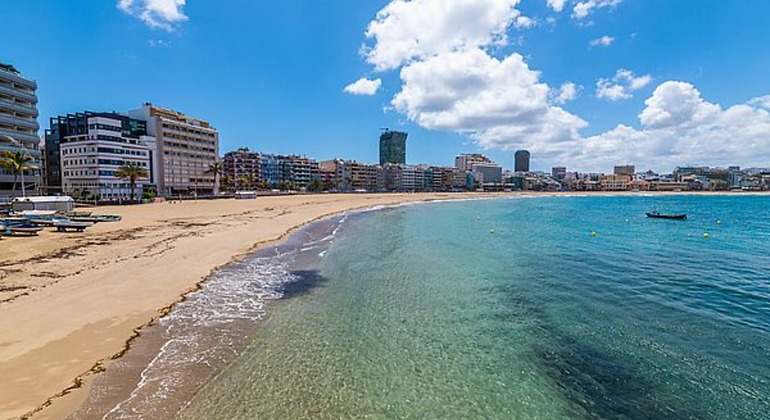 Una playa amplia con arenas blancas y un baño de aguas cristalinas en forma de concha