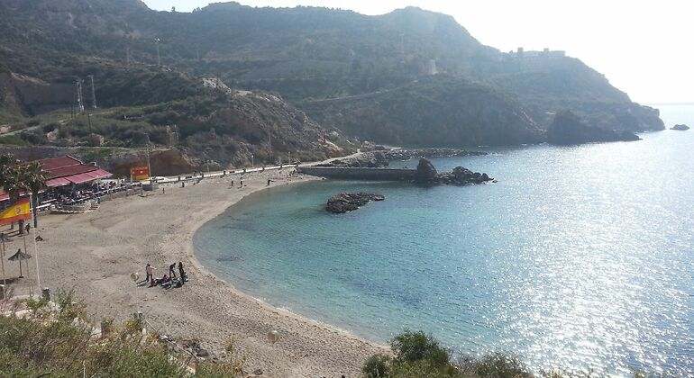 Playa con gente a lo lejos y aguas azules oscuras