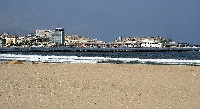 Una playa de arenas doradas que tiene como fondo la ciudad de Melilla