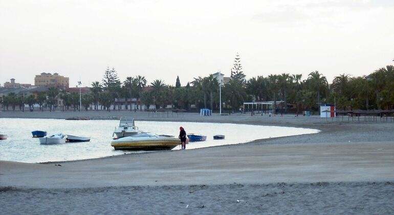 Playa gris, lancha, mujer con gorra roja
