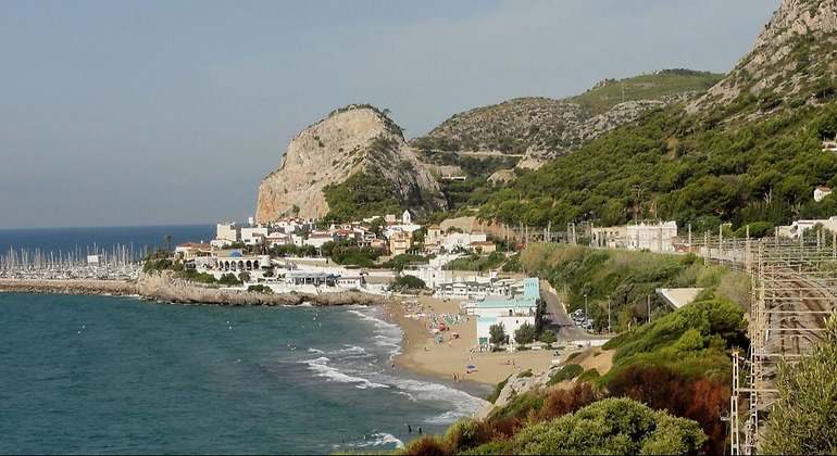 Playa urbana con un restaurante en plena arena antes de entrar al baño de la bahía. Está rodeada de acantilados y al fondo se puede ver el puerto