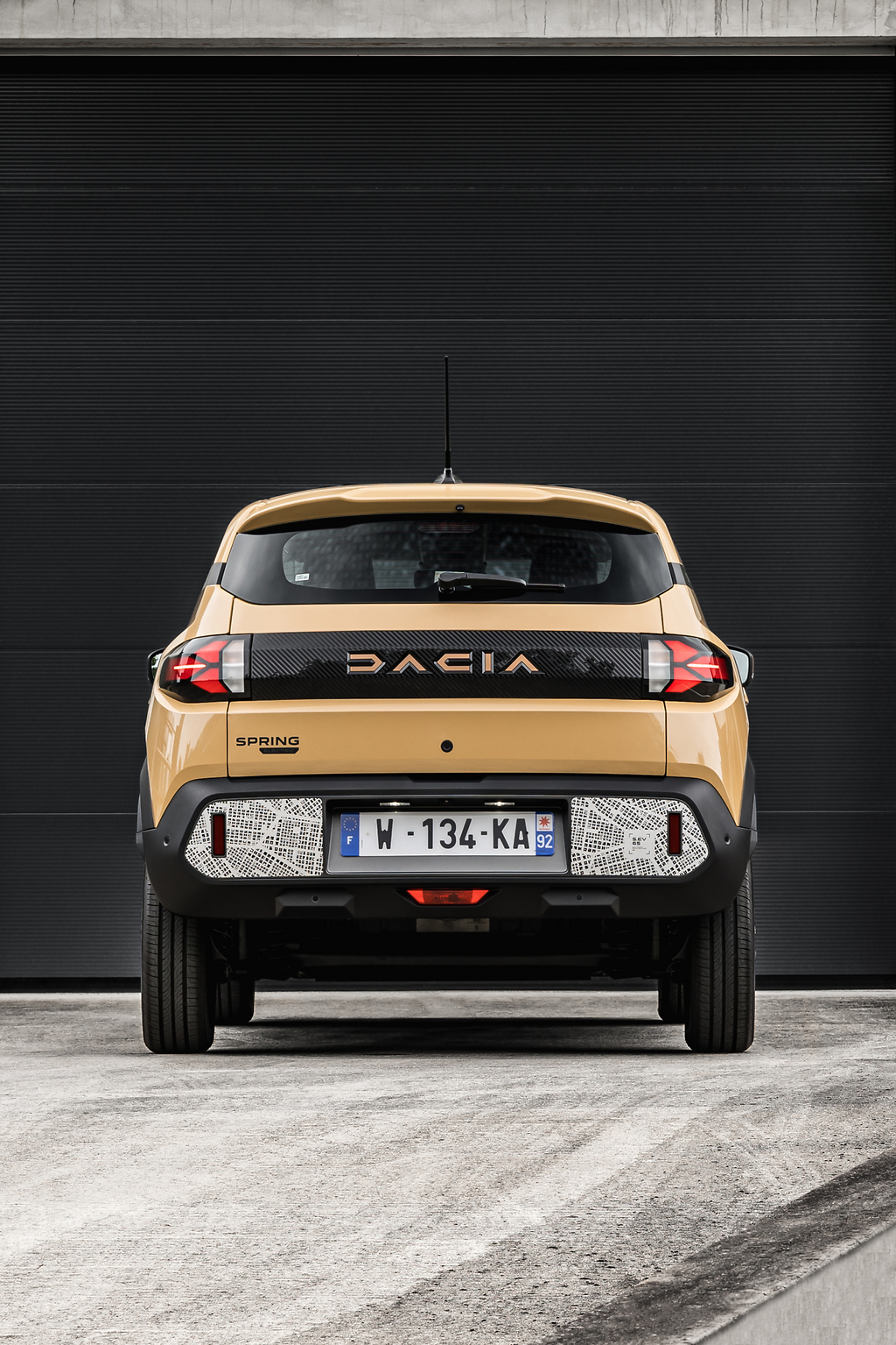 Dacia Spring 2024. El modelo se distingue por sus dos franjas negras, una en la parte delantera y otra en la parte trasera, de aspecto brillante, con estrías mate específicas en la parte trasera, enmarcadas por la firma luminosa en forma de "Y" de la marca.