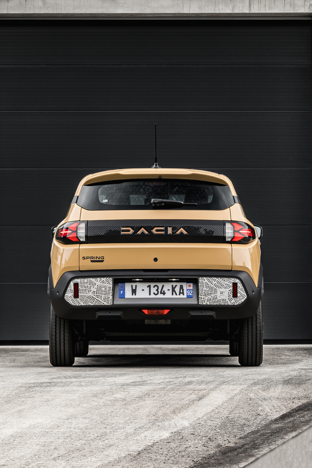 Dacia Spring 2024. El modelo se distingue por sus dos franjas negras, una en la parte delantera y otra en la parte trasera, de aspecto brillante, con estrías mate específicas en la parte trasera, enmarcadas por la firma luminosa en forma de "Y" de la marca.