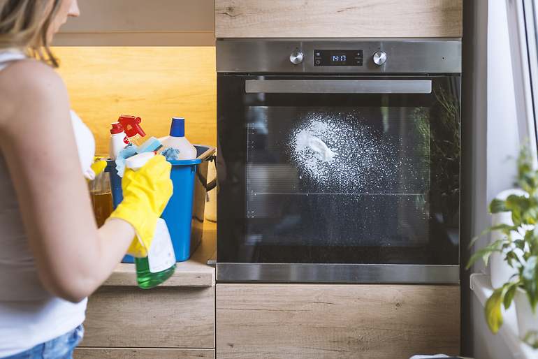 Imagen de una mujer limpiando un horno