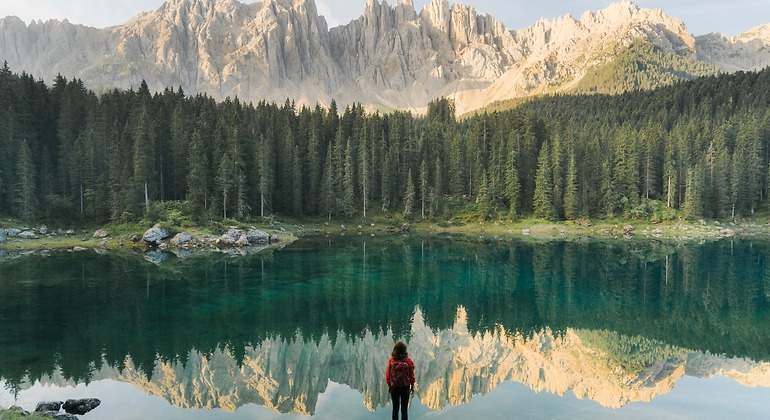 Mujer de pie y mirando el Lago di Carezza en Dolomitas
