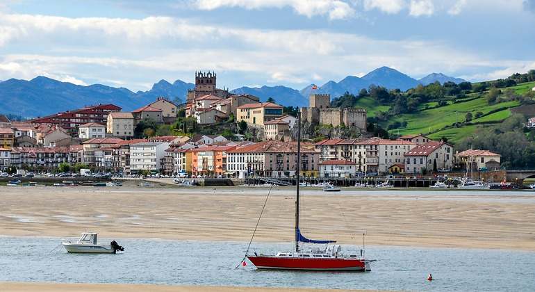 Yates y barcos pesqueros en la bahía cerrada del Mar Cantábrico en el telón de fondo de la montaña y la ciudad de San Vicente de la Barquera