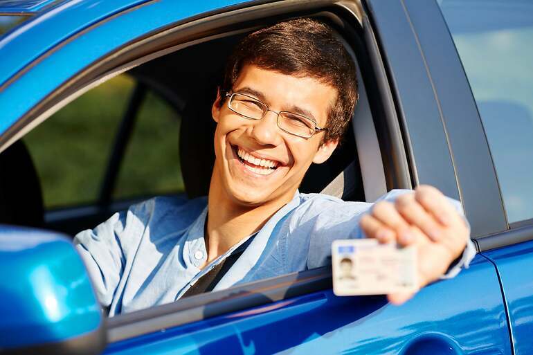 Joven con gafas muestra carnet de conducir desde el coche