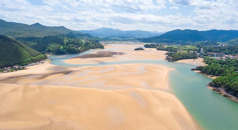 Vista aérea de la reserva bisphere de Urdaibai un basto arenal con un río en medio y vegetación a los lados