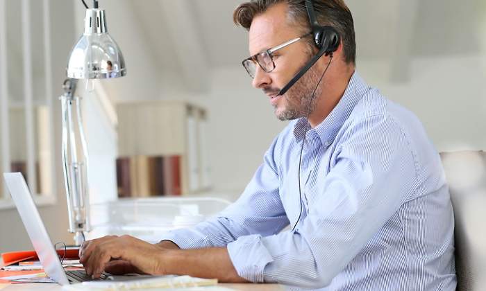 Un hombre teletrabaja con su ordenador y unos auriculares