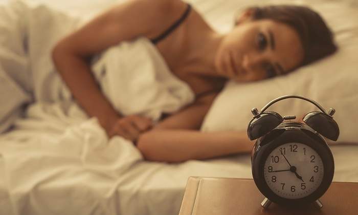 Una-mujer-despierta-tirada-en-cama-y-mirando-el-despertador-iStock.jpg