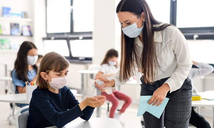 Una profesora da clase con la mascarilla puesta