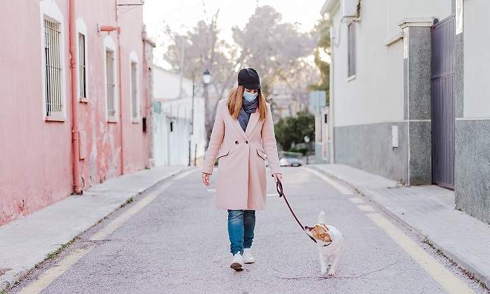 Mujer-caucasica-en-la-calle-usando-mascarilla-y-caminando-con-su-perro-iStock.jpg