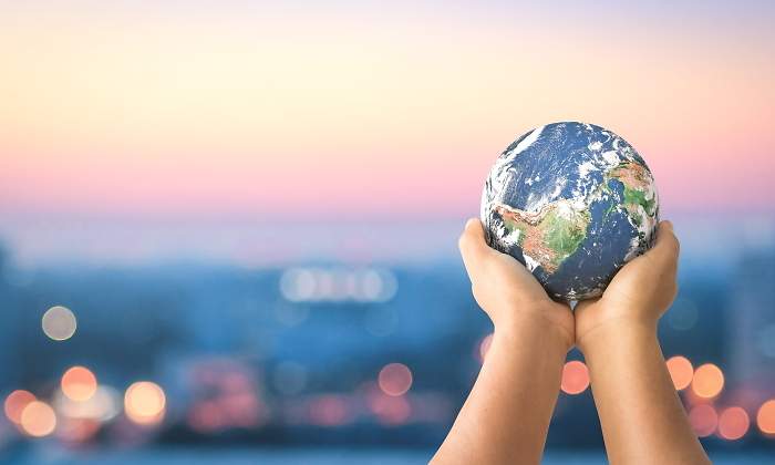 Unas manos sostienen el planeta con la ciudad al fondo