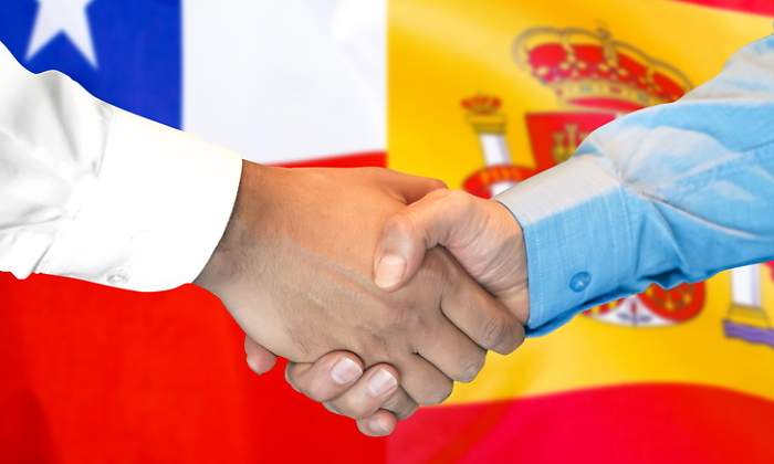 Apretn de manos con las banderas de Chile y Espaa de fondo