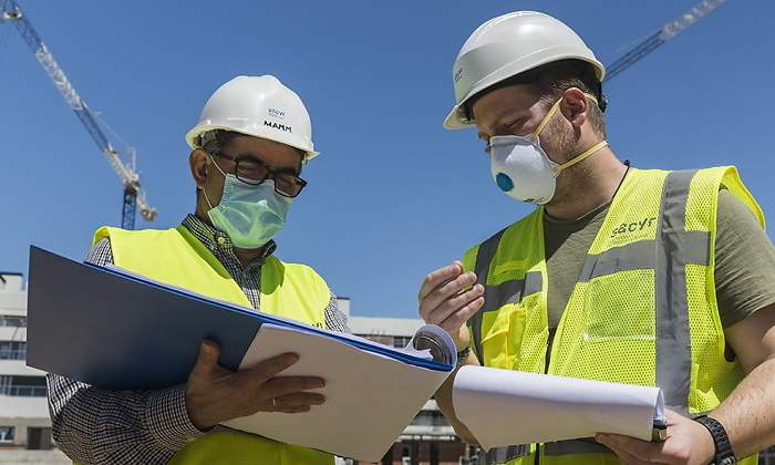 Dos trabajadores de Sacyr inspeccionan documentos en una obra