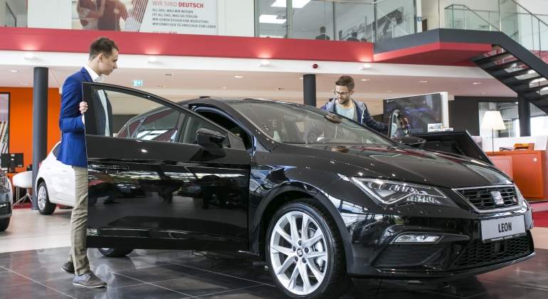 Jóvenes mirando un coche en un concesionario.