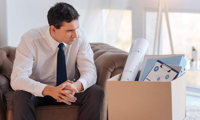 Un hombre mira serio a una caja con sus pertenencias tras perder su empleo