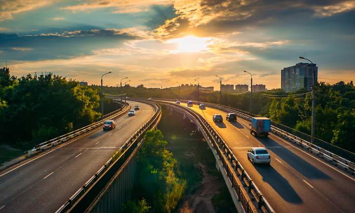 Coches circulan por una autopista al atardecer