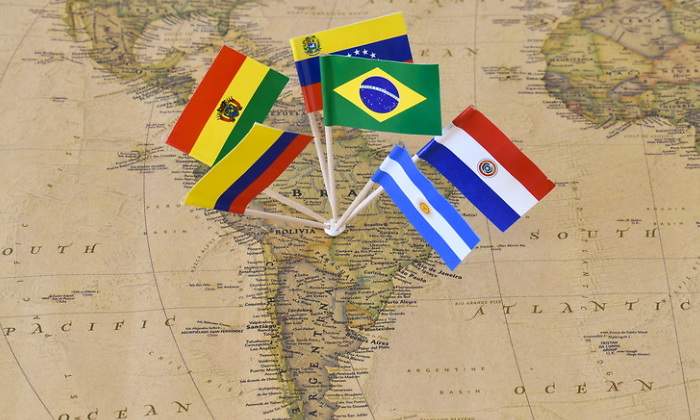 Mapa de Amrica Latina con varias banderas saliendo de Brasil