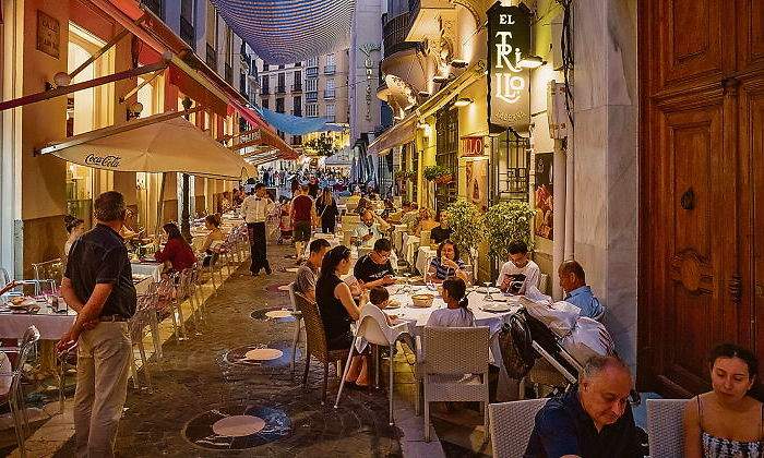 Gente cenando en restaurantes en la noche malaguea