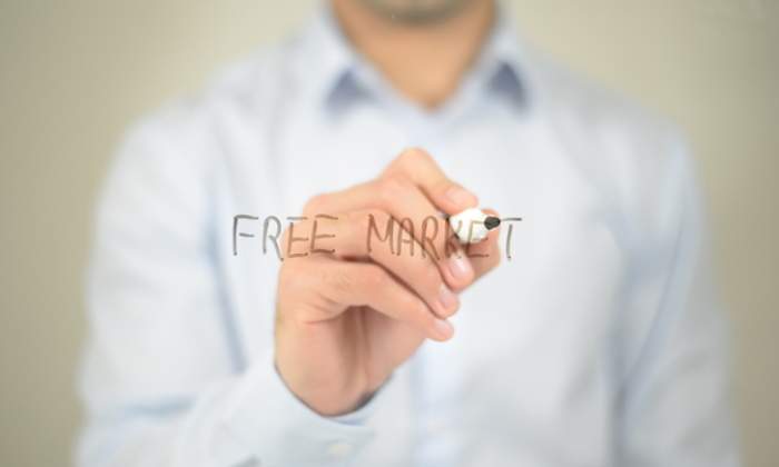 Un hombre escribe free market con un rotulador