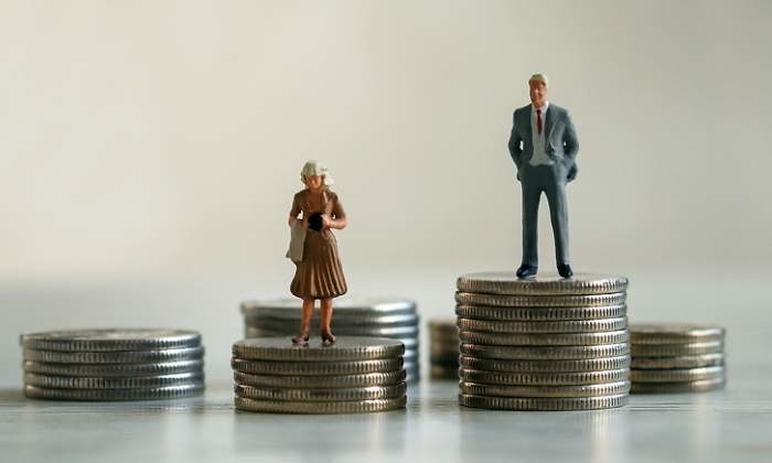 Representacin de la brecha salarial con el mueco de un hombre subido a una montaa de monedas ms alta que su equivalente mujer
