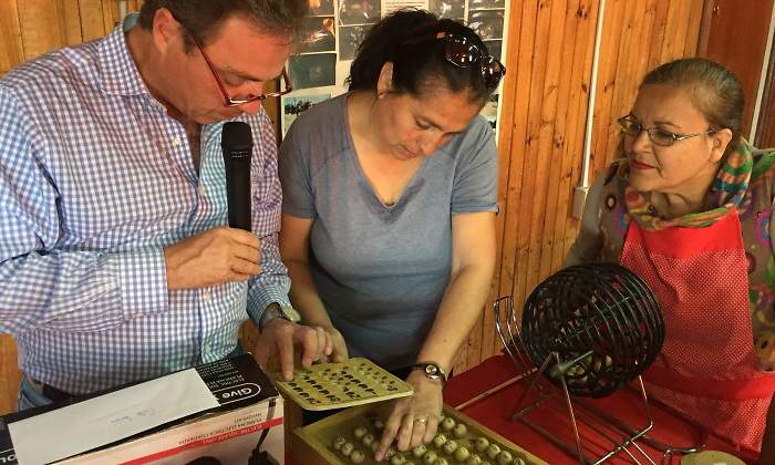 Un hombre lee los nmeros del bingo en presencia de dos mujeres