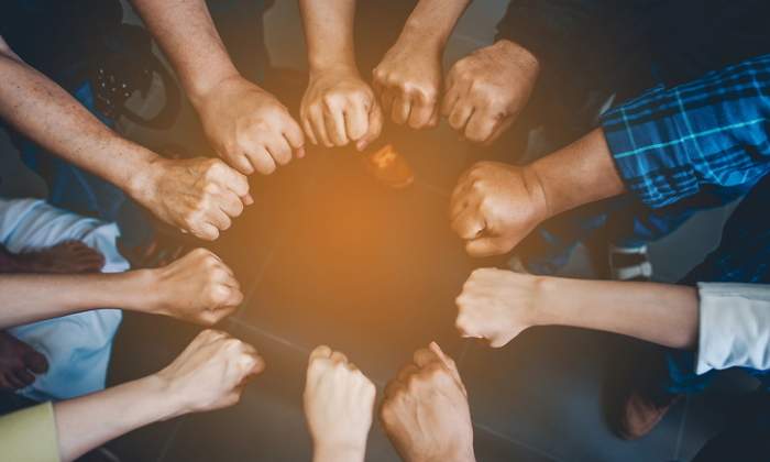 Varias personas unen sus manos para trabajar unidas