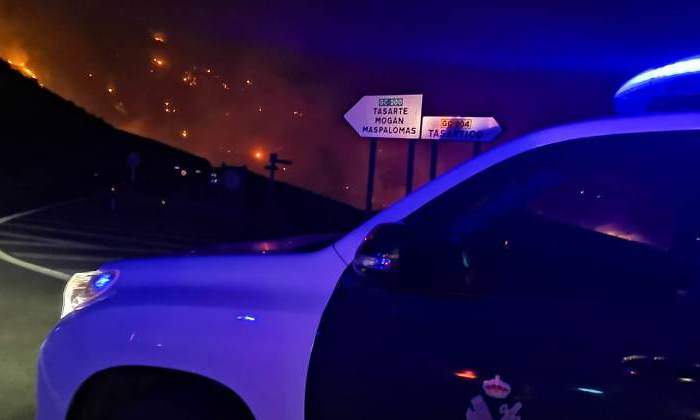 Un coche de la Guardia Civil en Canarias con un incendio al fondo