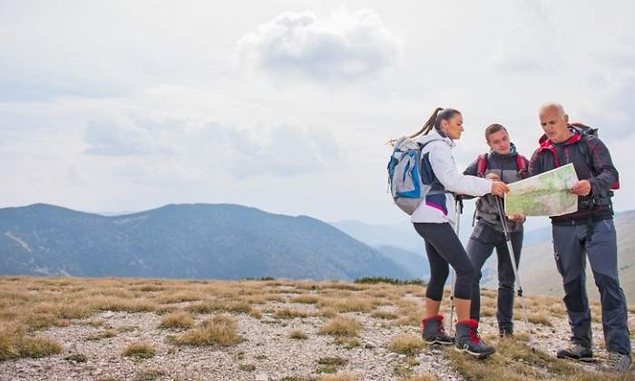 Tres personas miran un mapa en lo alto de una ladera