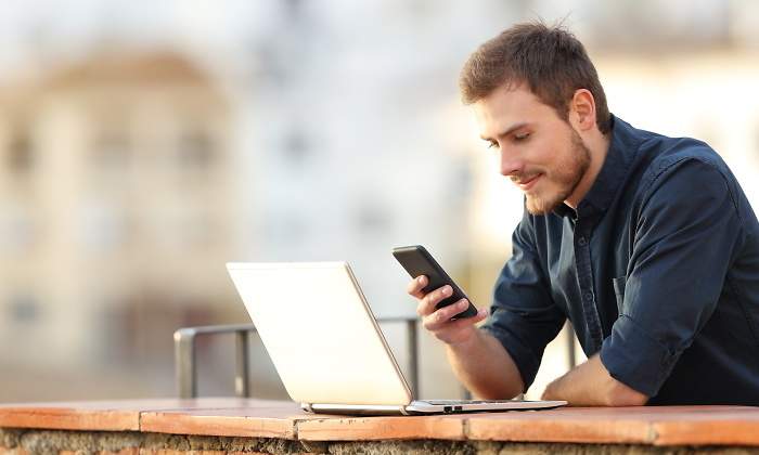 hombre-comprueba-portatil-movil-aire-libre-dreamstime.jpg