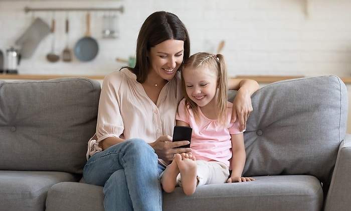 Una-madre-con-su-hija-mirando-el-movil-sentadas-en-el-sofa-iStock.jpg
