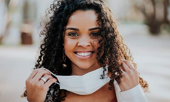 Una-chica-morena-con-el-pelo-rizo-poniendose-la-mascarilla-iStock.jpg