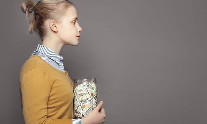 Una mujer sostiene un frasco lleno de dinero