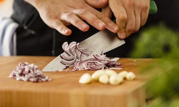 Una-persona-cortando-sobre-una-tabla-cebolla-morada-iStock.jpg