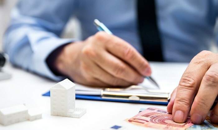 hombre-firma-dinero-casitas-istock.jpg