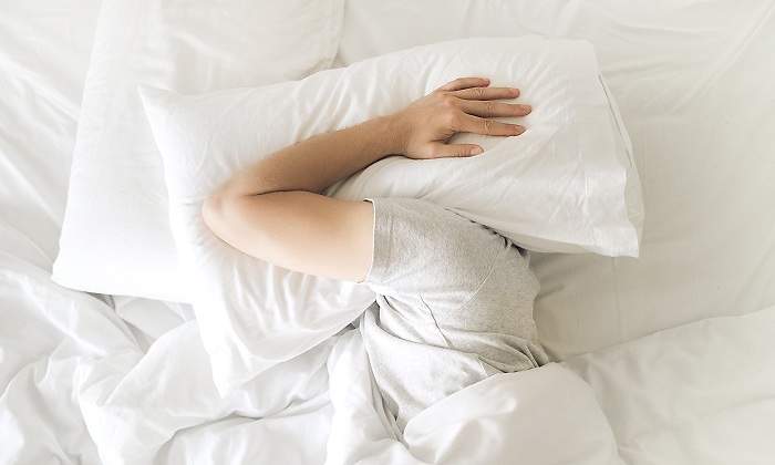 Una-persona-escondiendo-su-cabeza-con-una-almohada-iStock.jpg