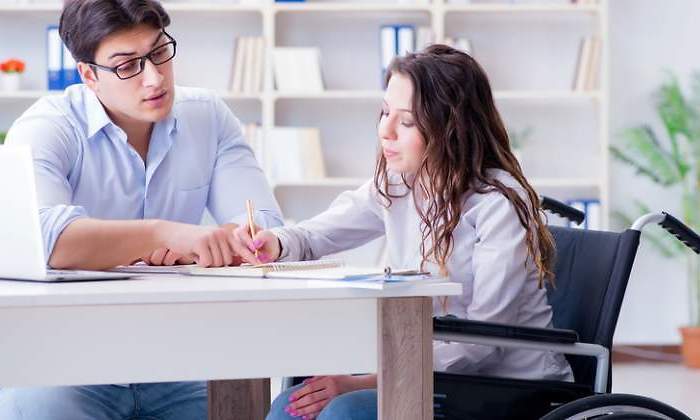 Una chica en silla de ruedas estudia con un tutor