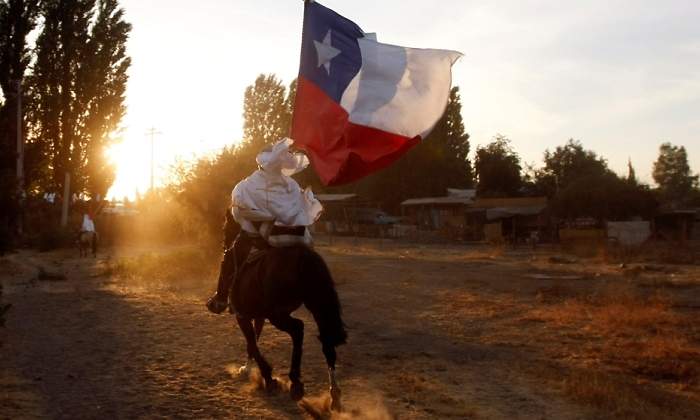 Una persona a caballo avanza con la bandera de Chile