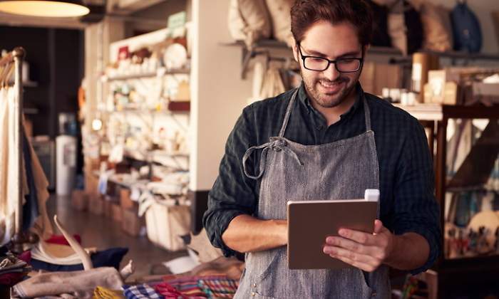 El propietario de una tienda de ropa y regalos usa una tablet