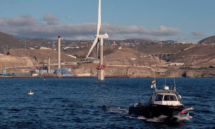 Un aerogenerador en el mar con un barco en primer plano