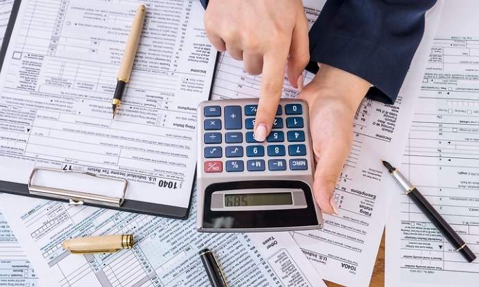Una persona hace cluclos de los impuestos con una calculadora