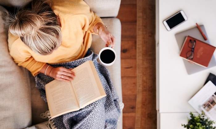 Mujer-leyendo-un-libro-en-el-sofa-con-una-manta-iStock.jpg