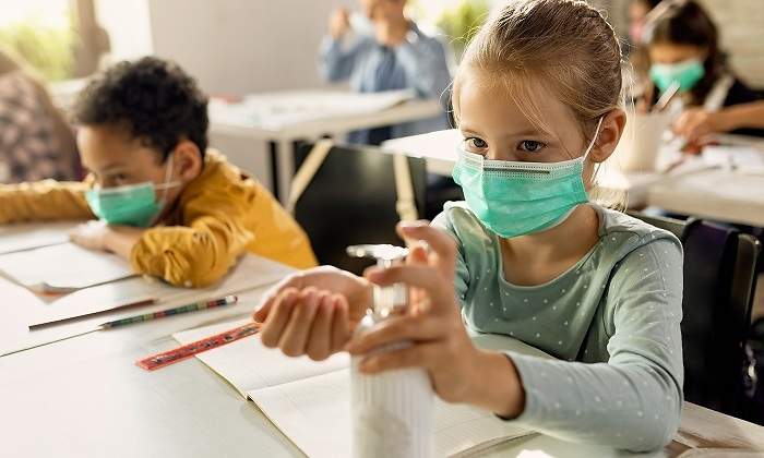 Nina-en-clase-con-gel-desinfectante-y-mascarilla-iStock.jpg