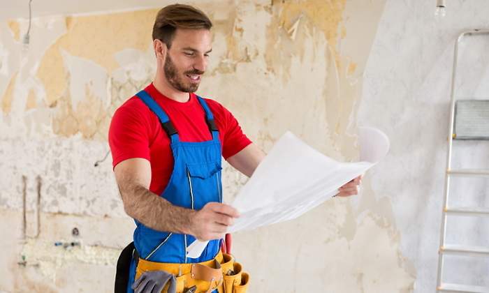 Un hombre mira unos planos para acometer la reforma de una vivienda